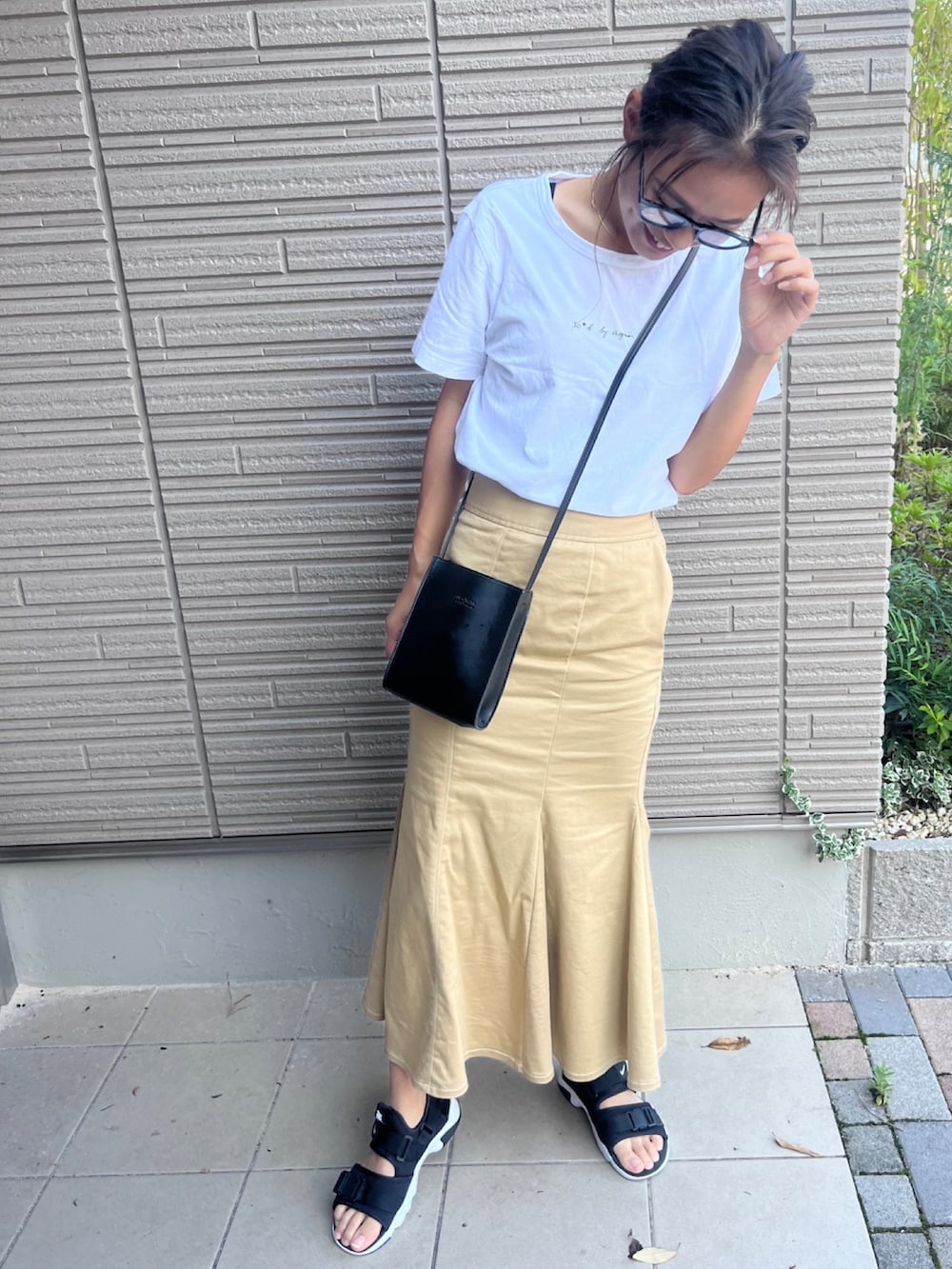 ブラック系のサンダル、ホワイト系のTシャツ/カットソー、ベージュ系のスカートを着用したレディースの夏コーディネートの2枚目の写真