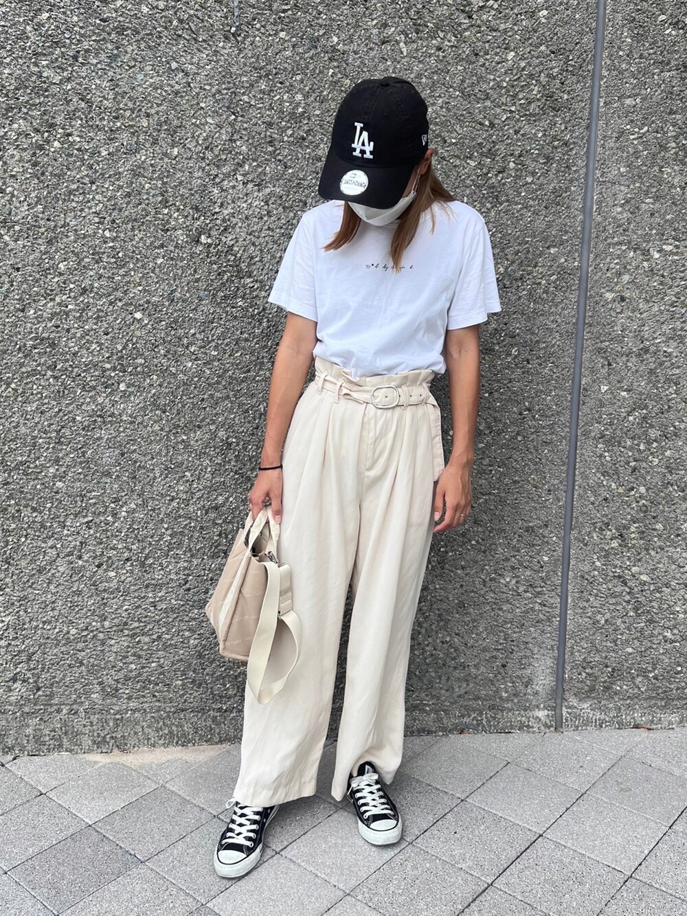 ベージュ系のパンツ、ベージュ系のハンドバッグ、ブラック系のスニーカーを着用したレディースの秋コーディネートの2枚目の写真