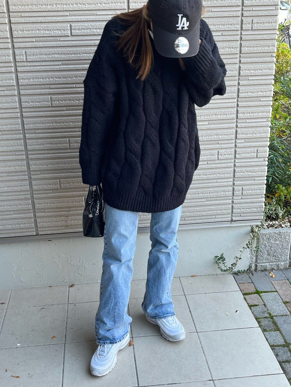 ブラック系のニット/セーター、ブルー系のデニムパンツ、ホワイト系のスニーカーを着用したレディースの冬コーディネートの2枚目の写真