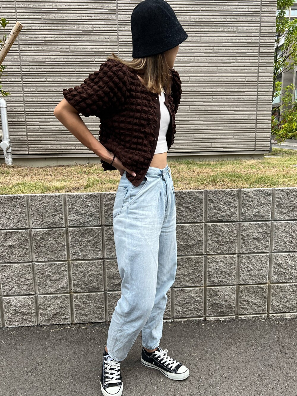 ブラック系のスニーカー、ブルー系のデニムパンツ、ブラウン系のトップスを着用したレディースの夏コーディネートの2枚目の写真