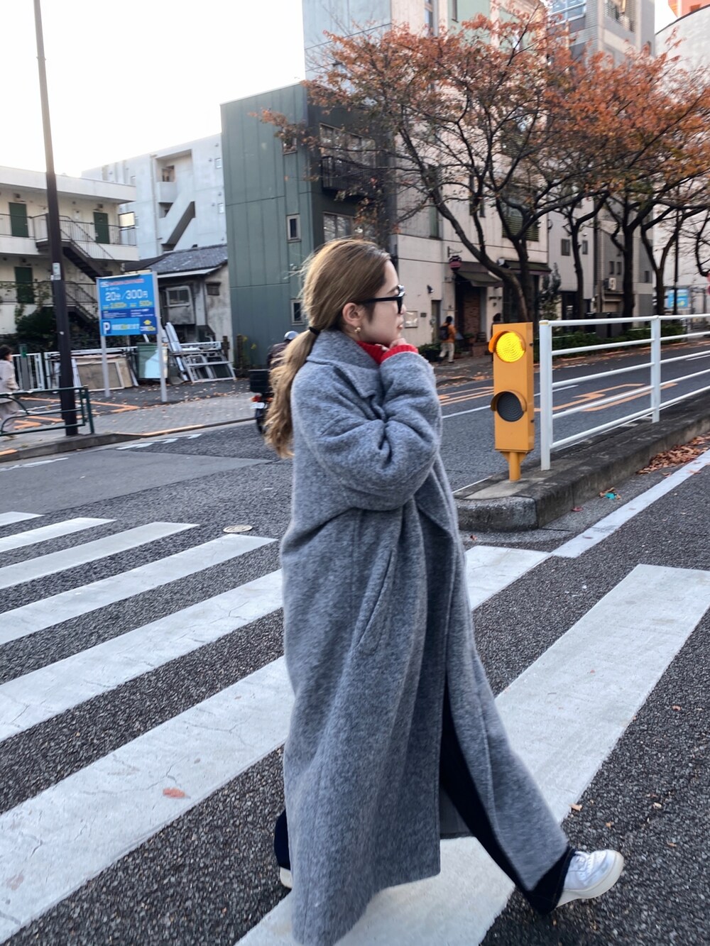 レッド系のニット/セーター、グレー系のチェスターコート、ブルー系のデニムパンツを着用したレディースの冬コーディネートの3枚目の写真
