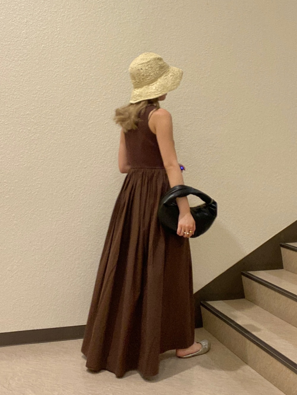 ブラック系のハンドバッグ、ブラウン系のワンピース、ベージュ系のハットを着用したレディースの夏コーディネートの2枚目の写真