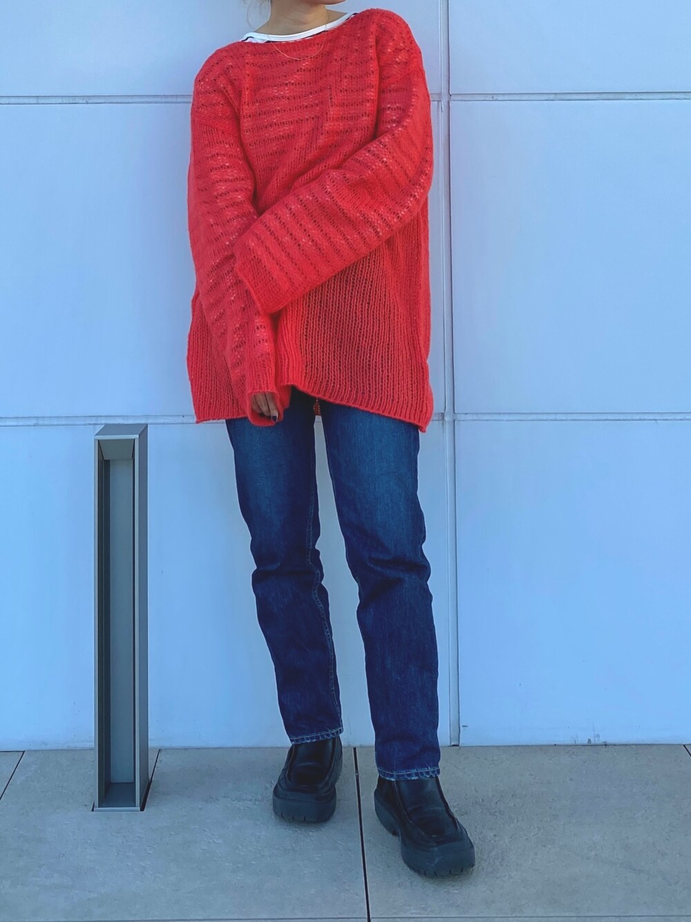 オレンジ系のニット/セーター、ブルー系のTシャツ/カットソーを着用したレディースの冬コーディネートの4枚目の写真