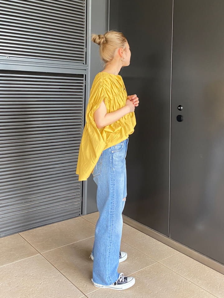 ブルー系のデニムパンツ、イエロー系のシャツ/ブラウス、ブラック系のキャミソールを着用したレディースの夏コーディネートの2枚目の写真