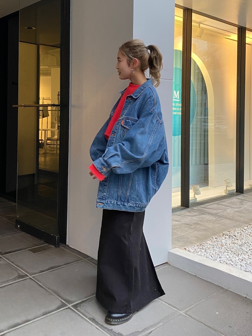 ブルー系のデニムジャケット、レッド系のスウェット、ブラック系のスカートを着用したレディースの冬コーディネートの2枚目の写真