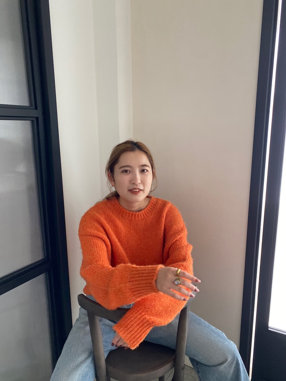 オレンジ系のニット/セーター、ブルー系のデニムパンツを着用したレディースの冬コーディネートの9枚目の写真