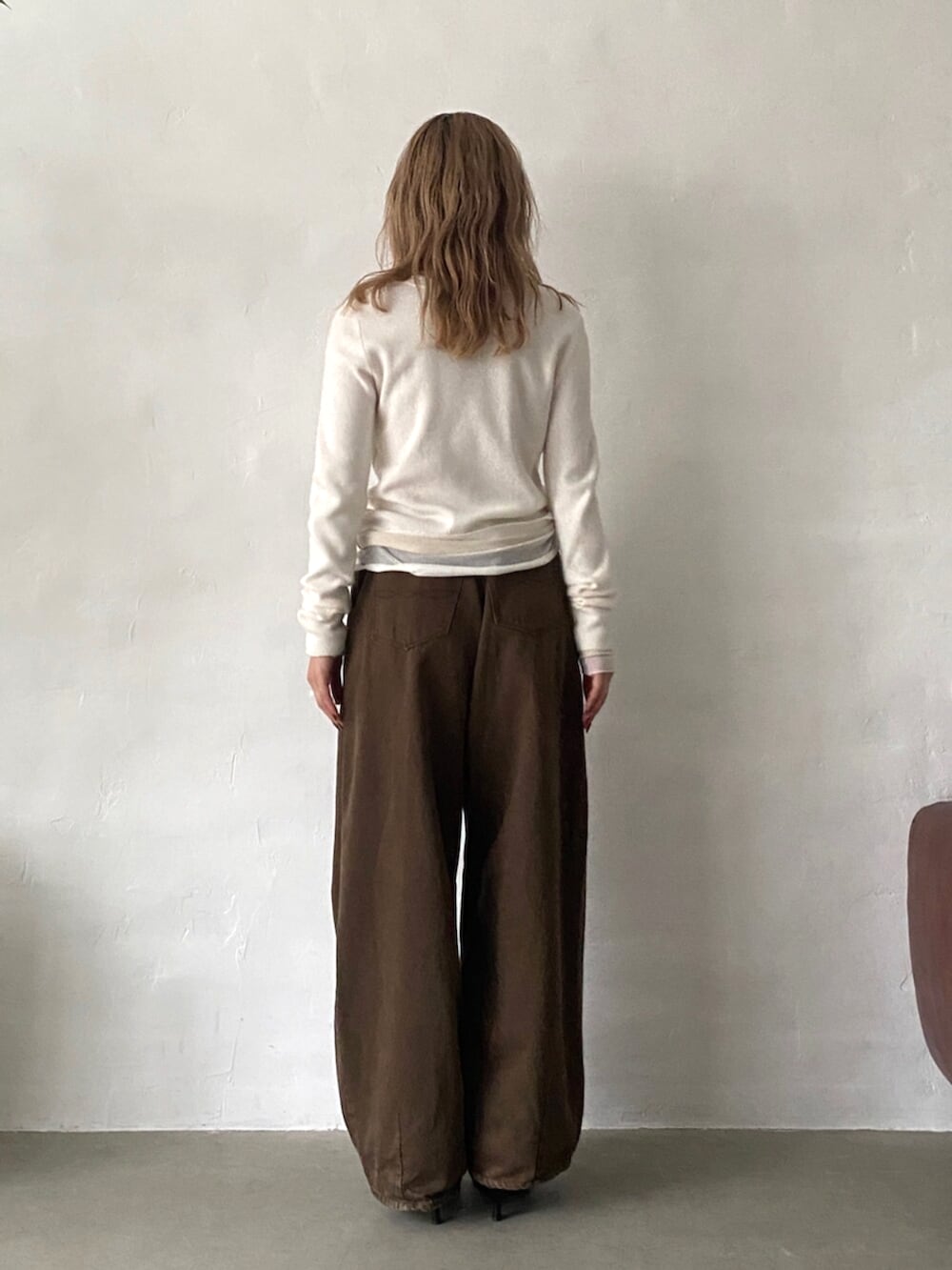 ブラック系のパンプス、ブラウン系のデニムパンツ、ホワイト系のニット/セーターを着用したレディースの秋コーディネートの3枚目の写真