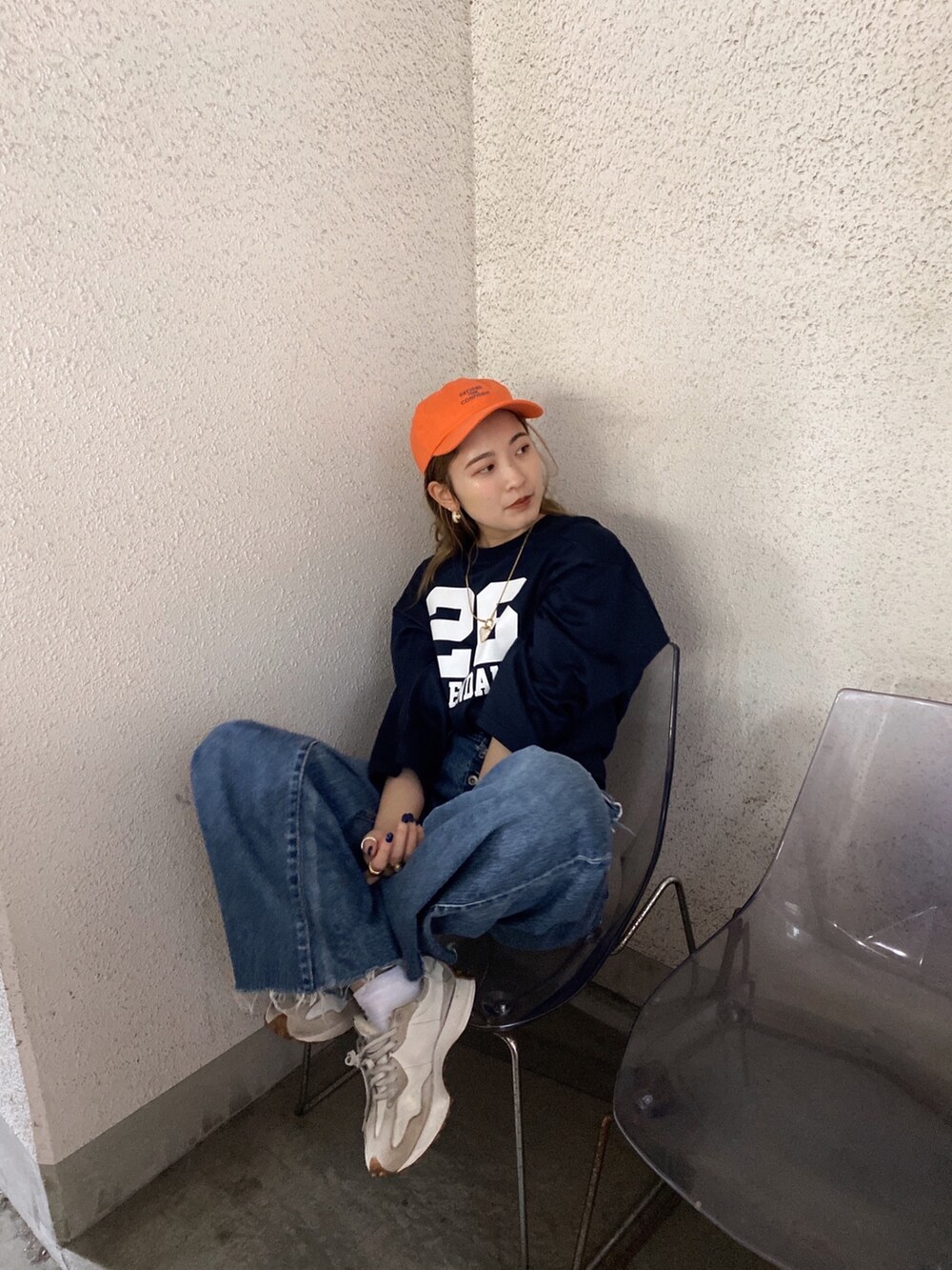 ブルー系のTシャツ/カットソー、ブルー系のデニムパンツ、オレンジ系のキャップを着用したレディースの春コーディネートの4枚目の写真