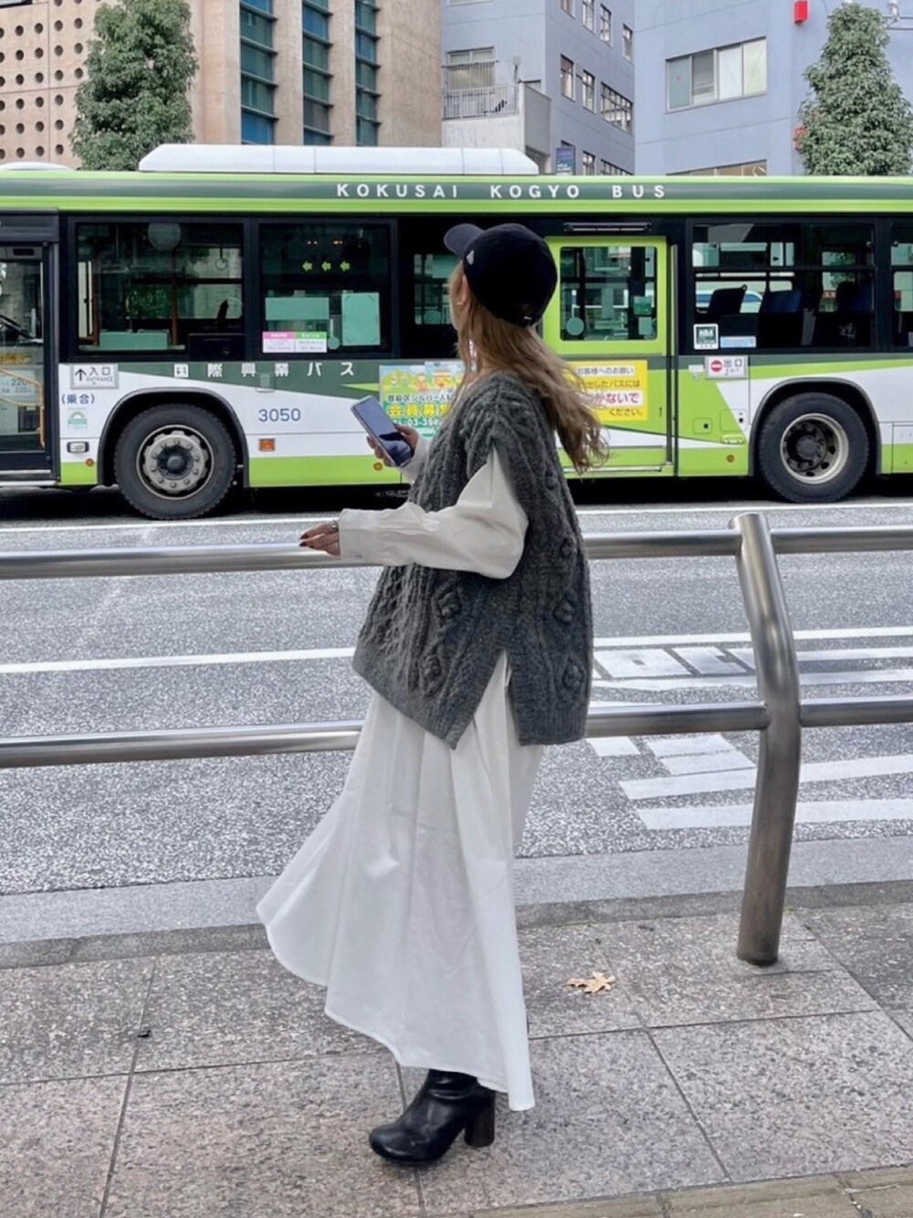 グレー系のニット/セーター、ブラック系のブーツ、ブラック系のワンピースを着用したレディースの冬コーディネートの4枚目の写真