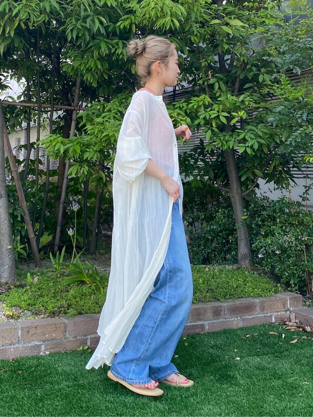 グリーン系のサンダル、ブルー系のデニムパンツ、ホワイト系のスニーカーを着用したレディースの夏コーディネートの2枚目の写真