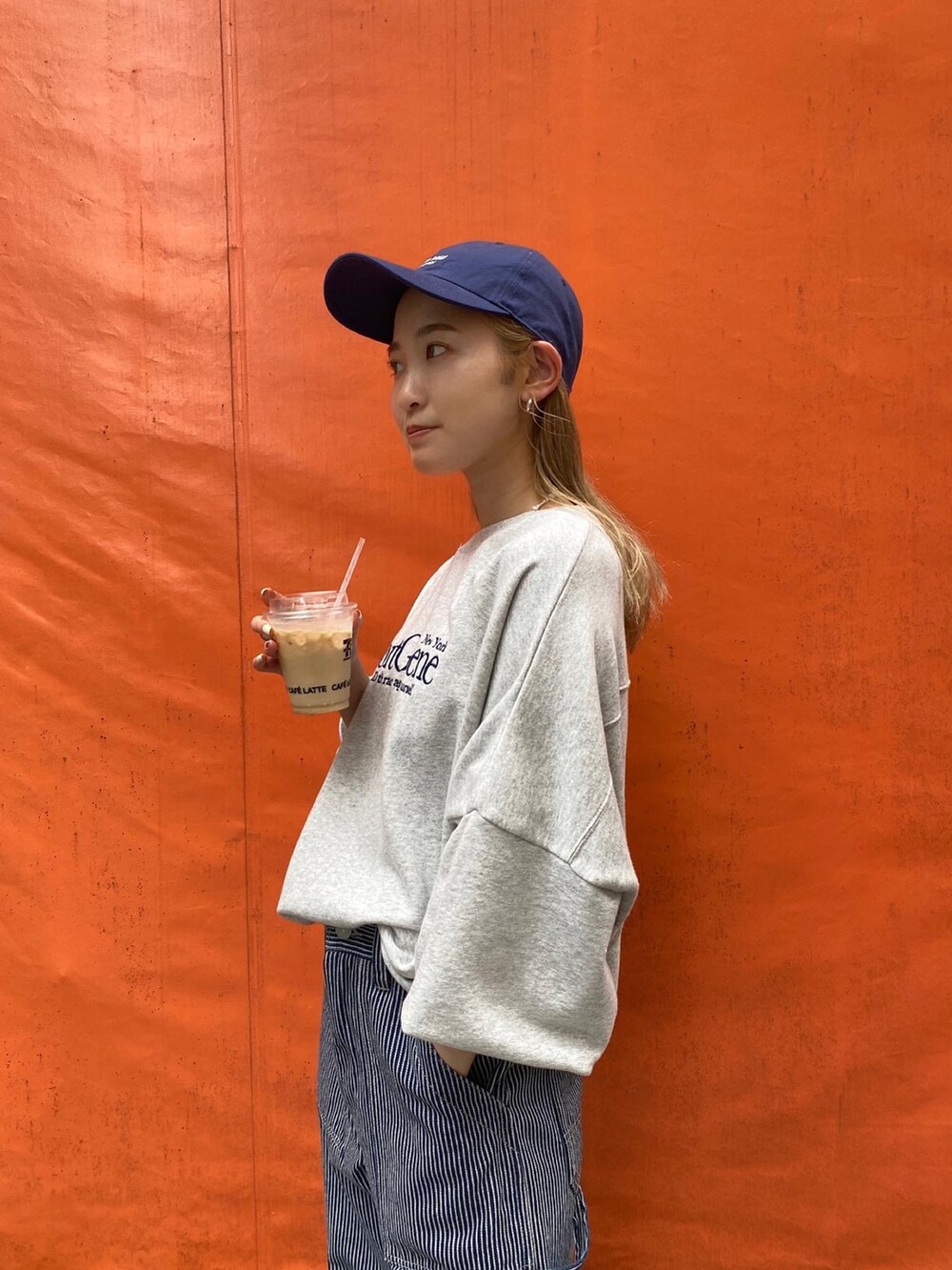 グレー系のスウェット、その他のデニムパンツ、ブルー系のキャップを着用したレディースの夏コーディネートの3枚目の写真