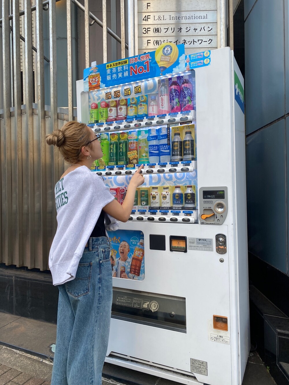 グレー系のスウェット、ブルー系のデニムパンツ、ブラック系のサンダルを着用したレディースの秋コーディネートの4枚目の写真