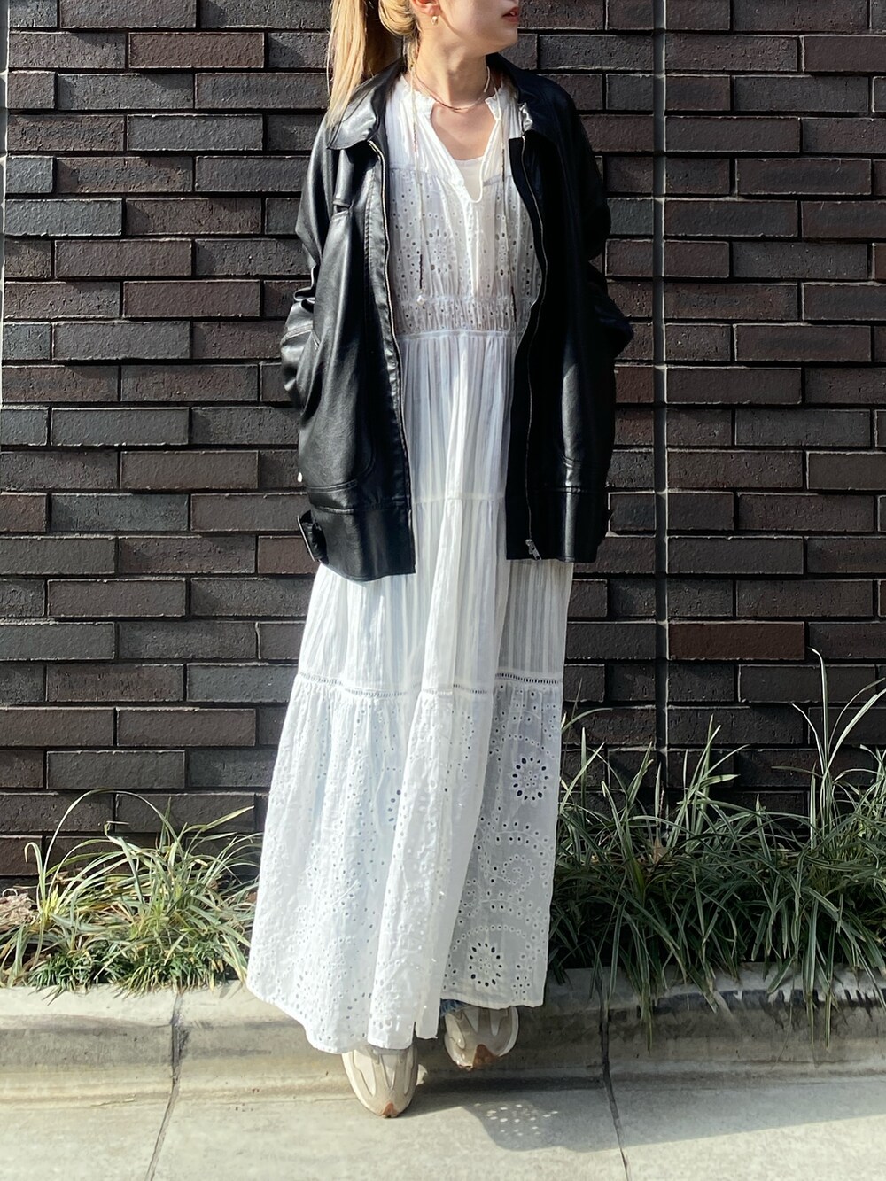 ブラック系のブルゾン、ホワイト系のワンピース、ブルー系のデニムパンツを着用したレディースの冬コーディネートの3枚目の写真