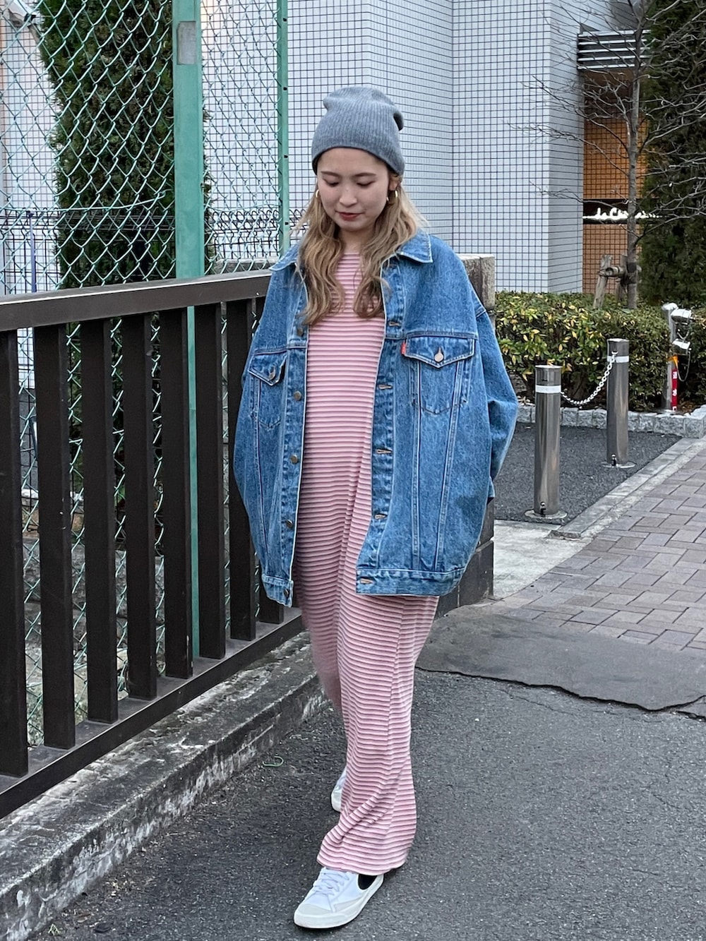 ピンク系のワンピース、ブルー系のデニムジャケット、グレー系のニットキャップ/ビーニーを着用したレディースの冬コーディネートの2枚目の写真