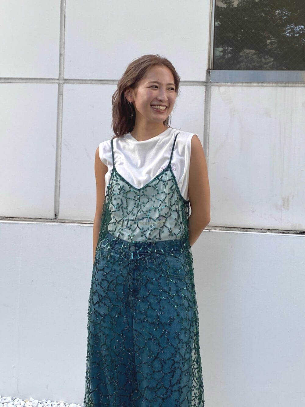 ブルー系のデニムパンツ、ホワイト系のタンクトップ、グリーン系のワンピースを着用したレディースの夏コーディネートの4枚目の写真