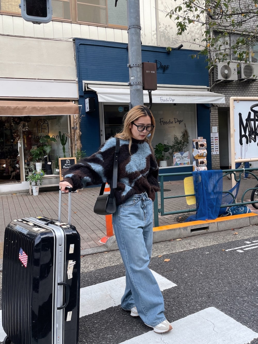 ブラウン系のニット/セーター、ブルー系のデニムパンツ、ブラック系のメガネを着用したレディースの秋コーディネートの2枚目の写真