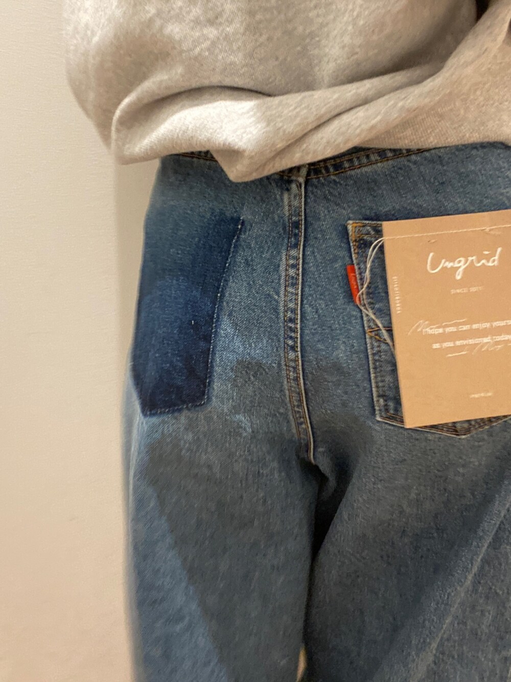 グレー系のスウェット、ブルー系のデニムパンツ、オレンジ系のキャップを着用したレディースの春コーディネートの2枚目の写真