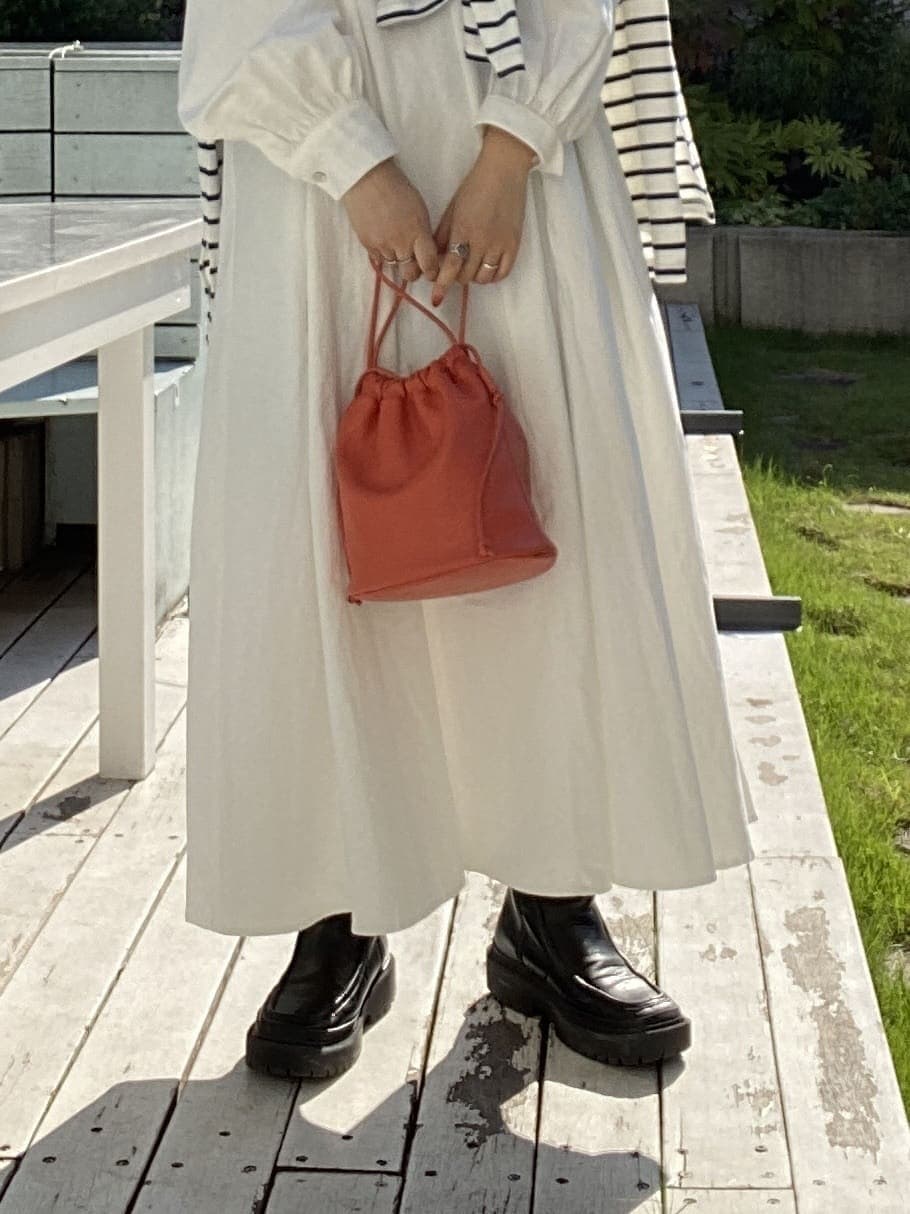 オレンジ系のハンドバッグ、オレンジ系のワンピース、ブルー系のTシャツ/カットソーを着用したレディースの秋コーディネートの6枚目の写真