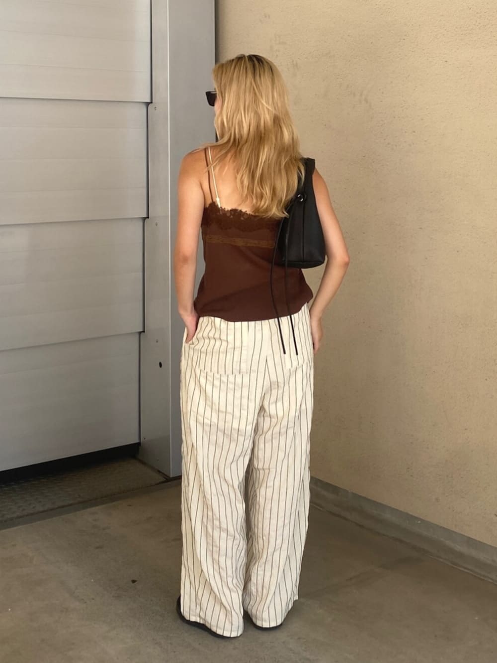 ホワイト系のその他パンツ、ブラウン系のTシャツ/カットソー、ブラック系のハンドバッグを着用したレディースの夏コーディネートの3枚目の写真