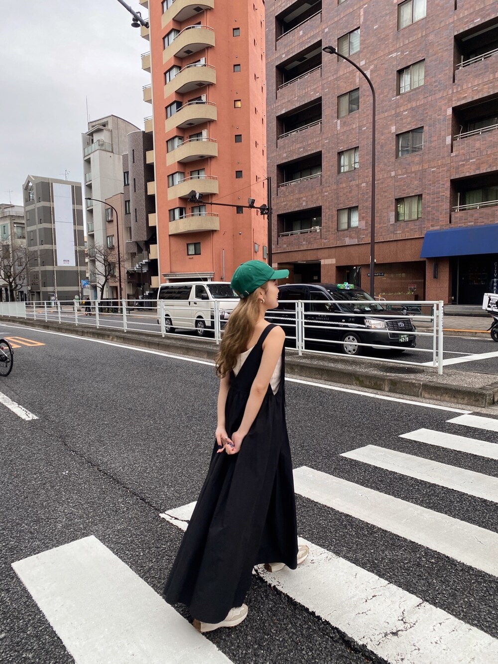 ブラック系のワンピース、ホワイト系のキャミソール、グリーン系のキャップを着用したレディースの春コーディネートの3枚目の写真