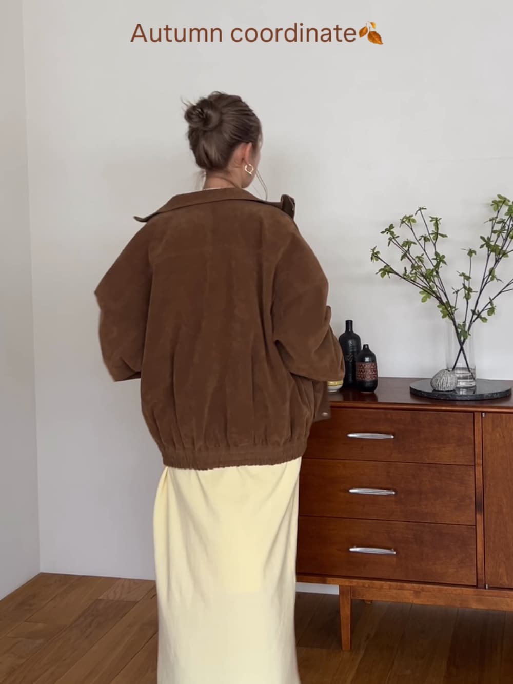 ブラウン系のブルゾン、イエロー系のワンピース、ホワイト系のネックレスを着用したレディースの秋コーディネートの2枚目の写真