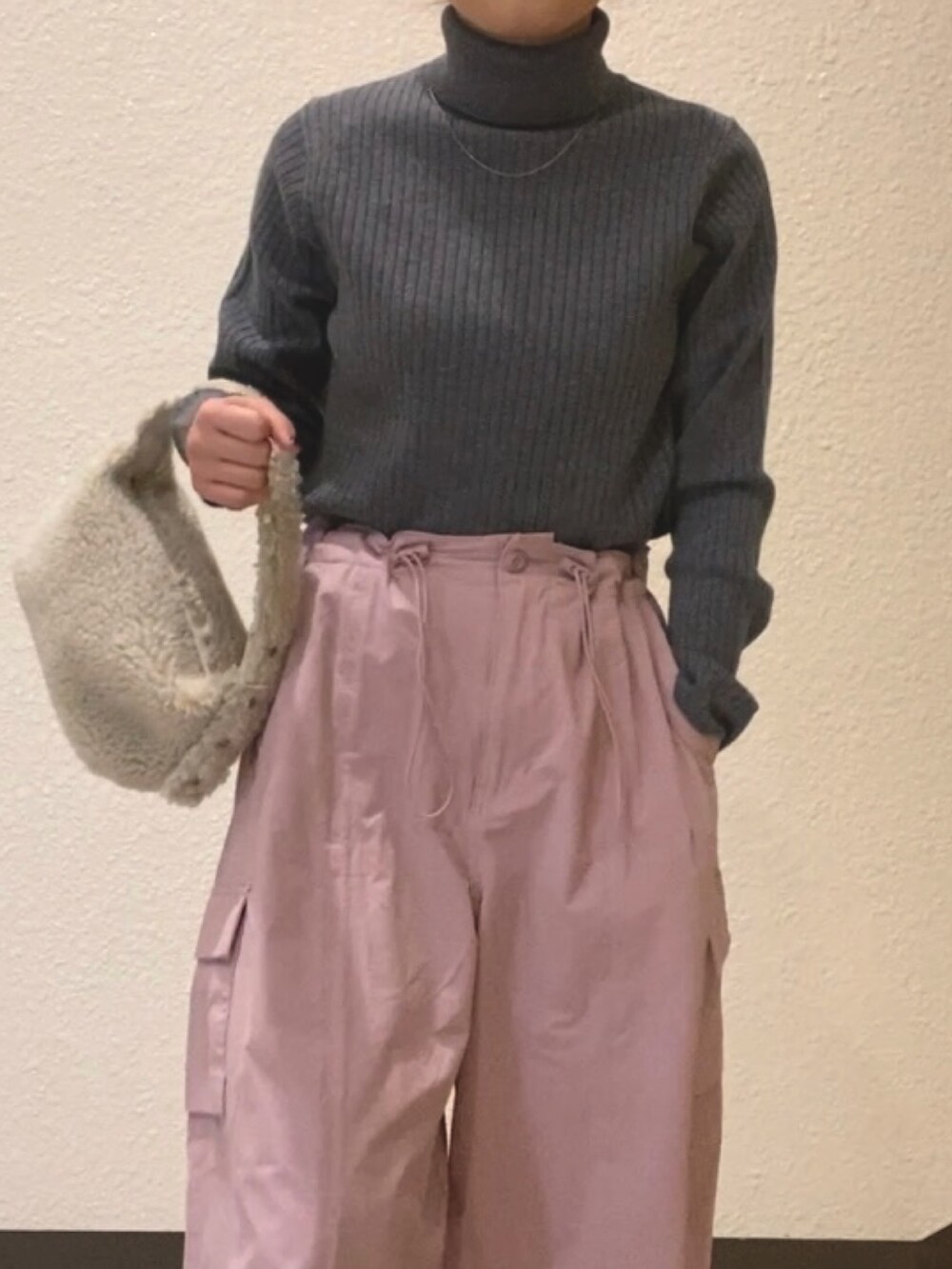 グレー系のニット/セーター、ピンク系のカーゴパンツ、ホワイト系のハンドバッグを着用したレディースの冬コーディネートの5枚目の写真