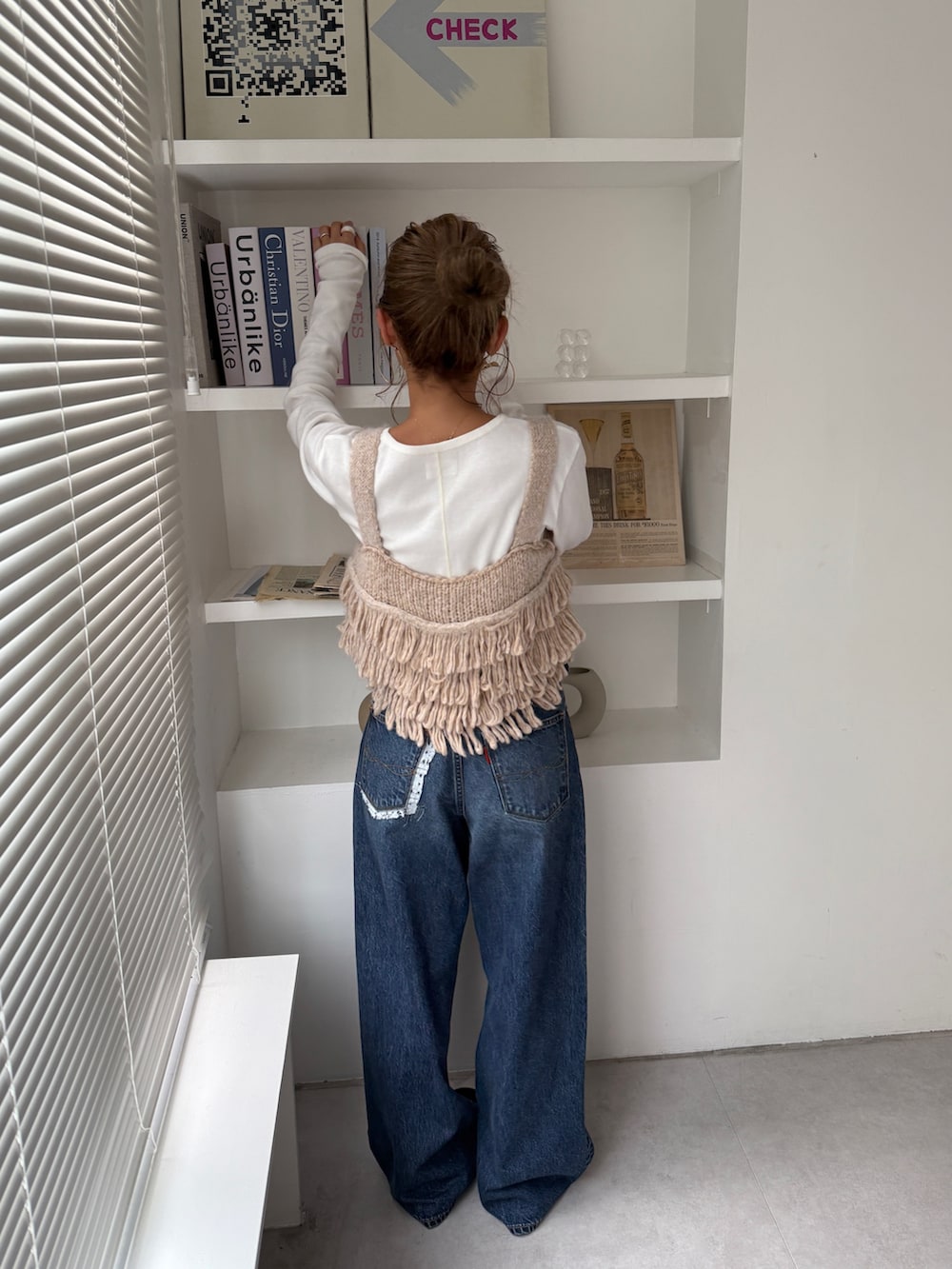 ホワイト系のニット/セーター、ブルー系のデニムパンツ、ブラック系のスリッポンを着用したレディースの秋コーディネートの4枚目の写真