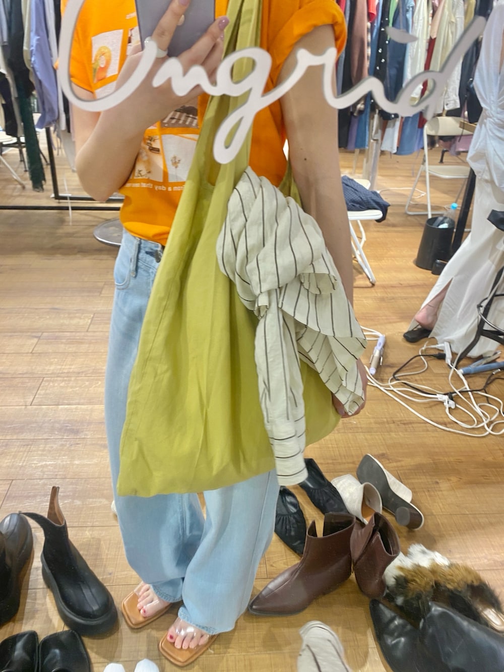 オレンジ系のTシャツ/カットソー、ブルー系のデニムパンツ、その他のサンダルを着用したレディースの春コーディネートの6枚目の写真