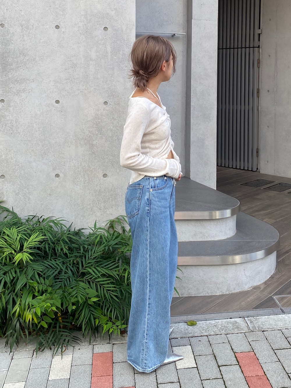 ホワイト系のニット/セーター、ブルー系のデニムパンツ、シルバー系のパンプスを着用したレディースの夏コーディネートの2枚目の写真
