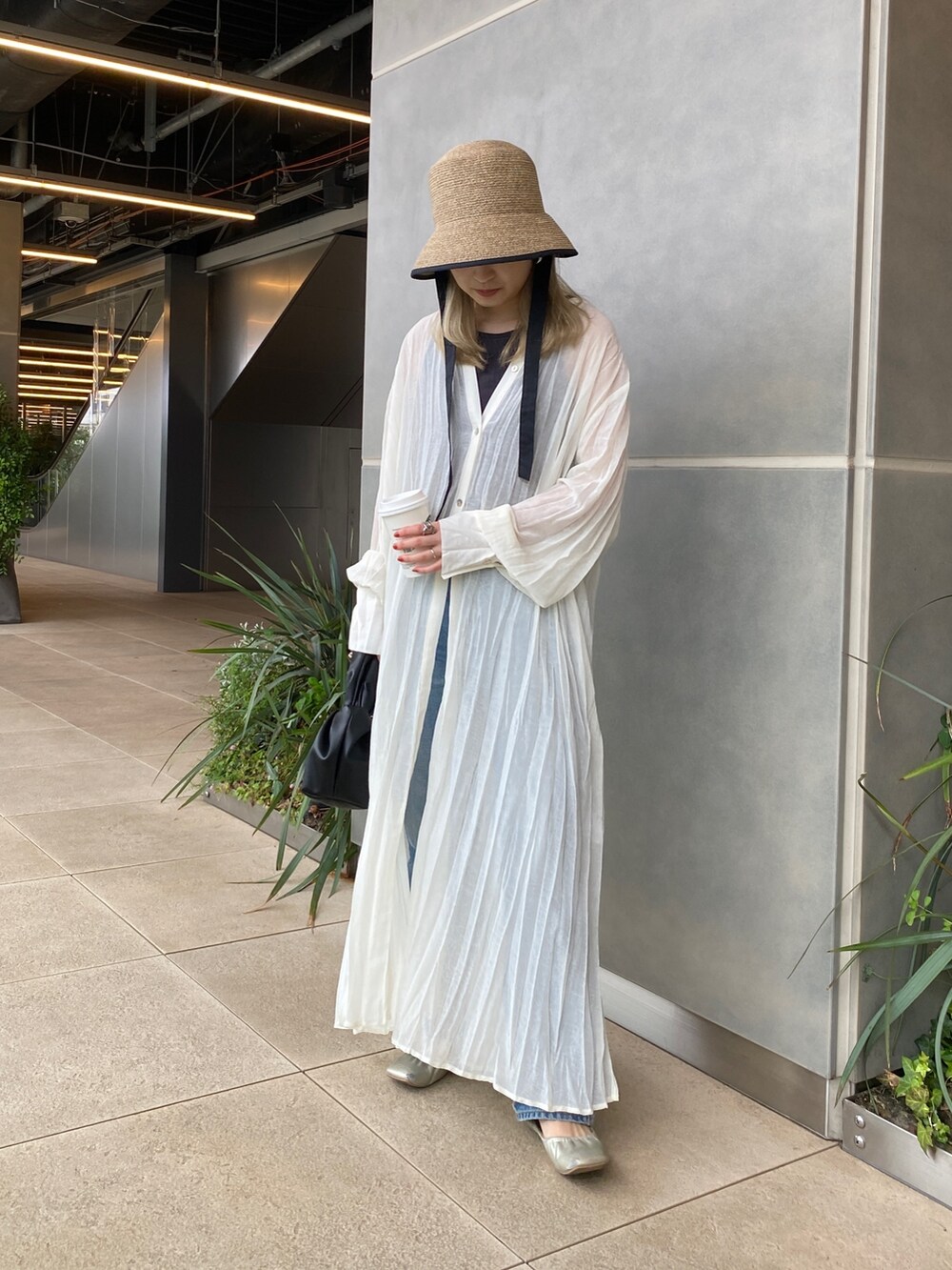 ホワイト系のワンピース、ブルー系のデニムパンツ、ブラック系のハンドバッグを着用したレディースの春コーディネートの2枚目の写真