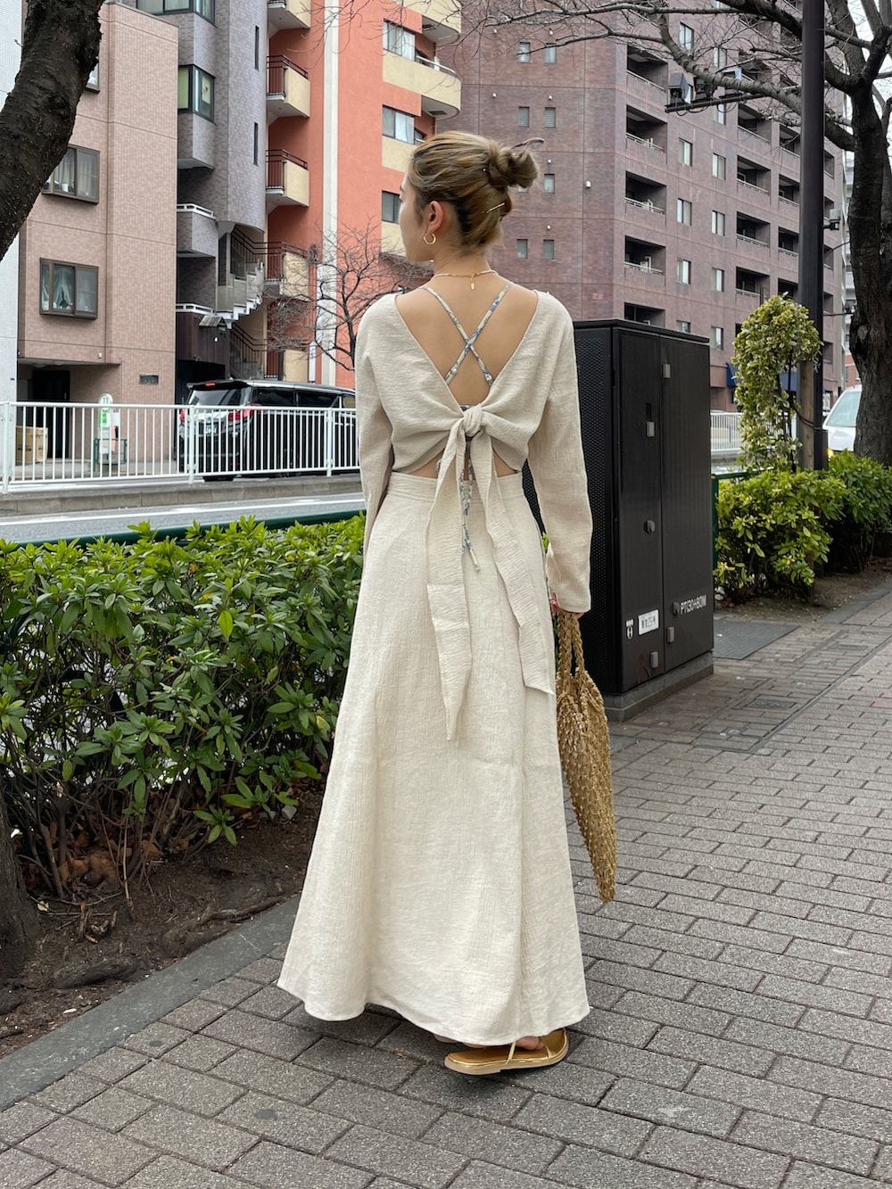 ホワイト系のワンピース、イエロー系のハンドバッグ、ゴールド系のサンダルを着用したレディースの春コーディネートの5枚目の写真