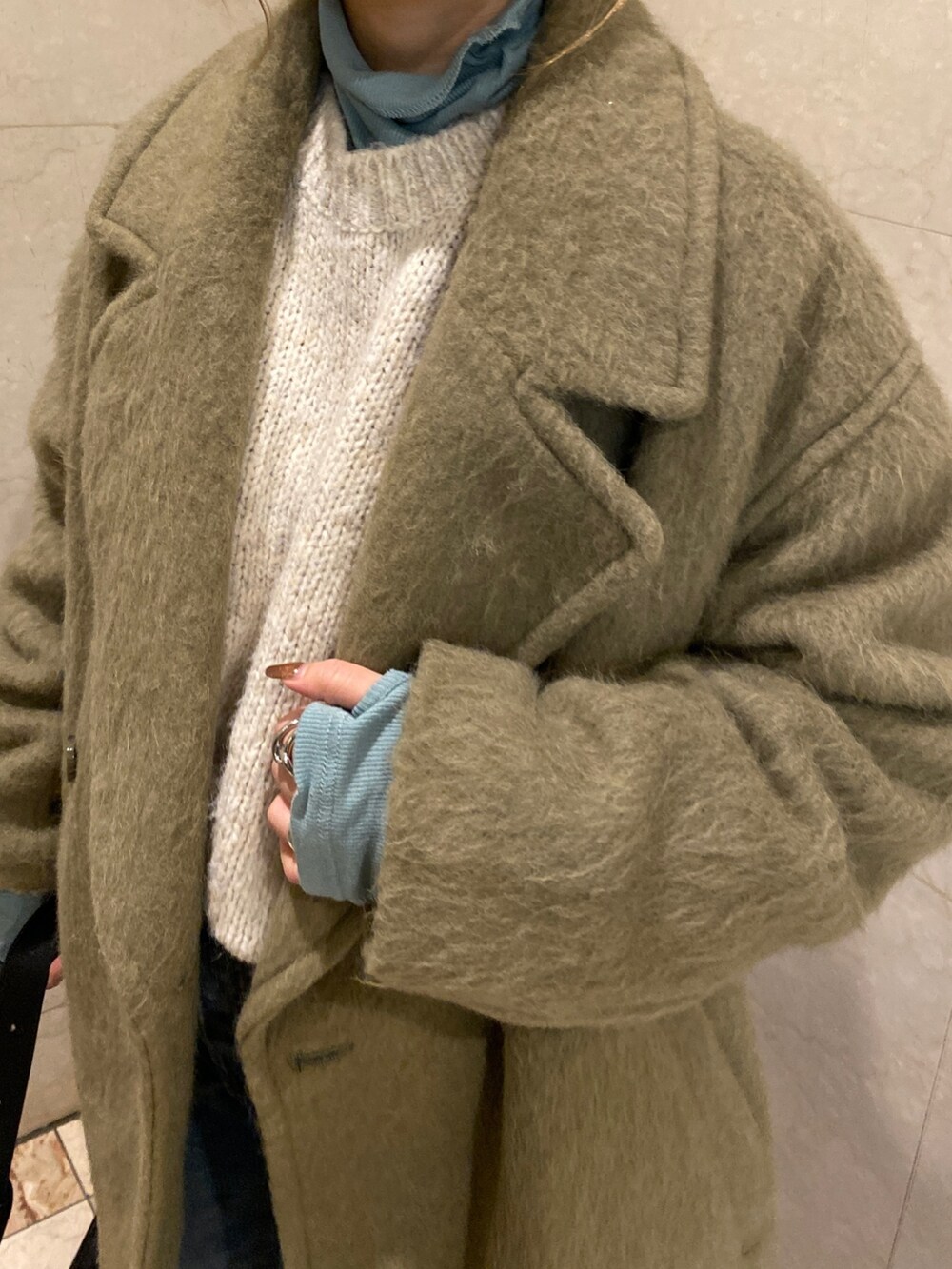 ホワイト系のニット/セーター、ブルー系のTシャツ/カットソー、グリーン系のピーコートを着用したレディースの冬コーディネートの7枚目の写真