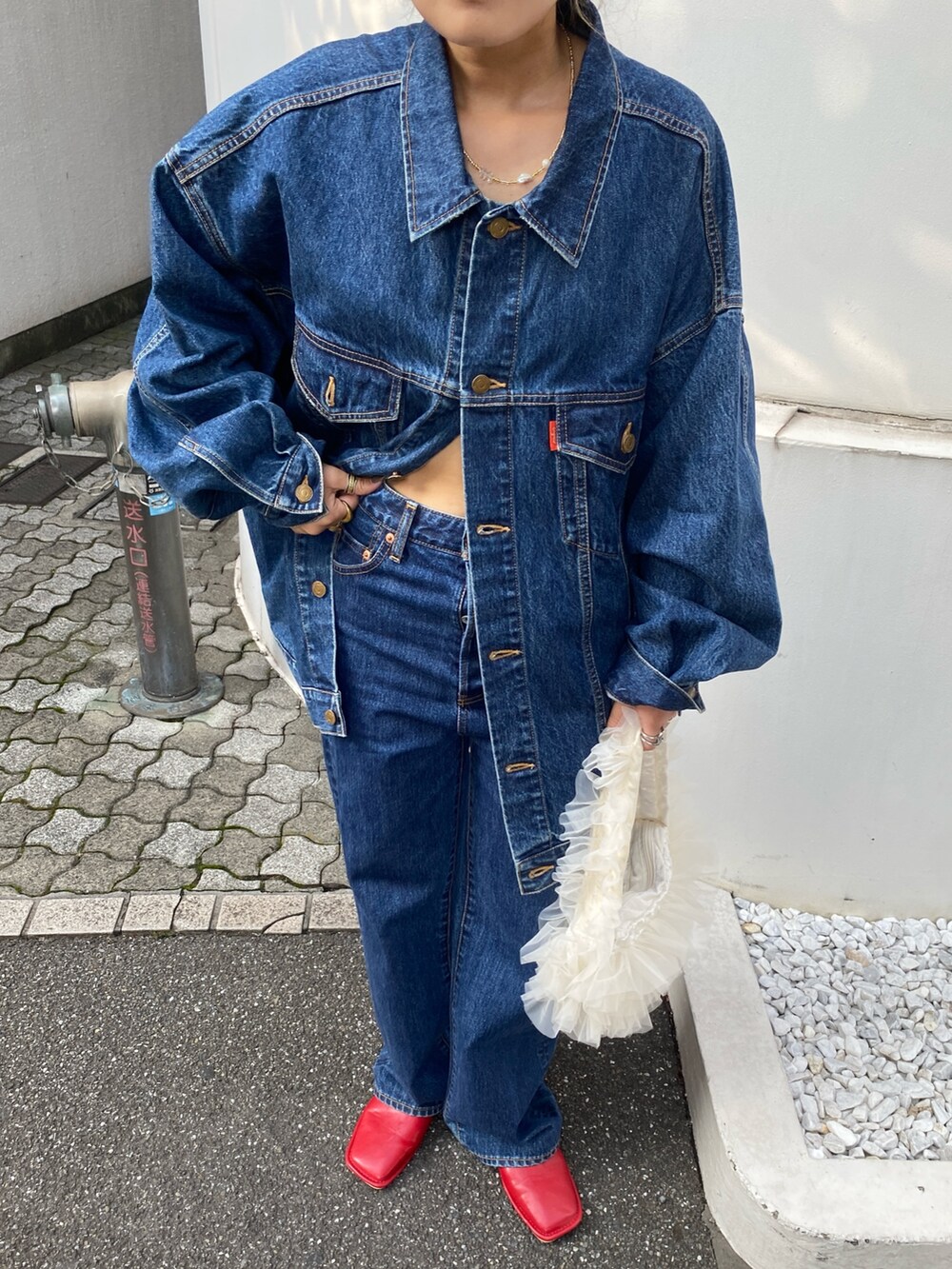 ブルー系のデニムジャケット、ブルー系のデニムパンツ、ホワイト系のショルダーバッグを着用したレディースの夏コーディネートの6枚目の写真