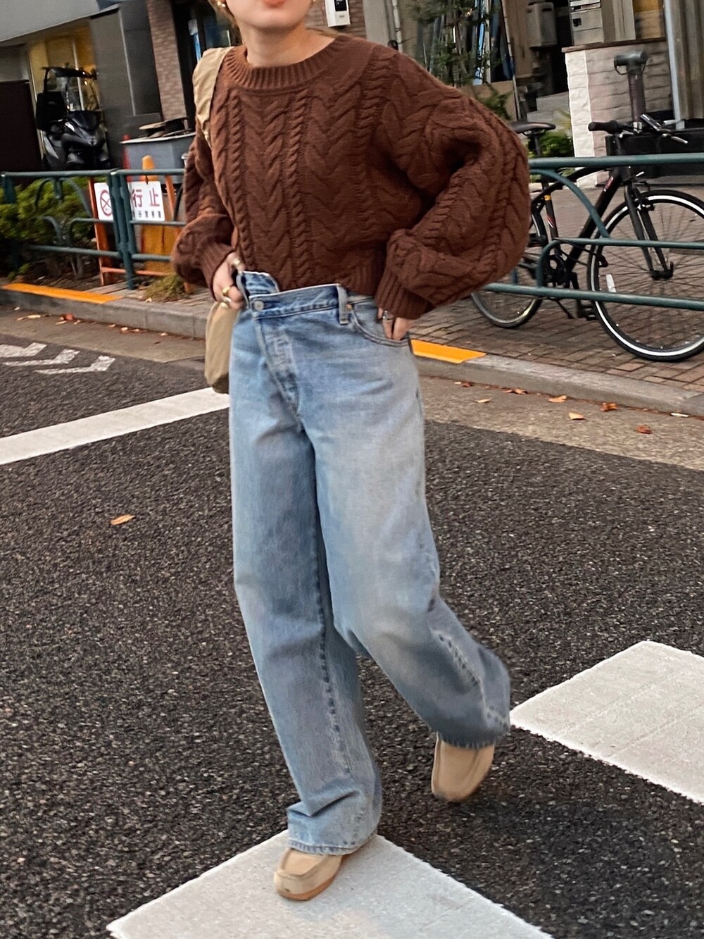 ブラウン系のニット/セーター、ブルー系のデニムパンツ、ベージュ系のハンドバッグを着用したレディースの冬コーディネートの2枚目の写真