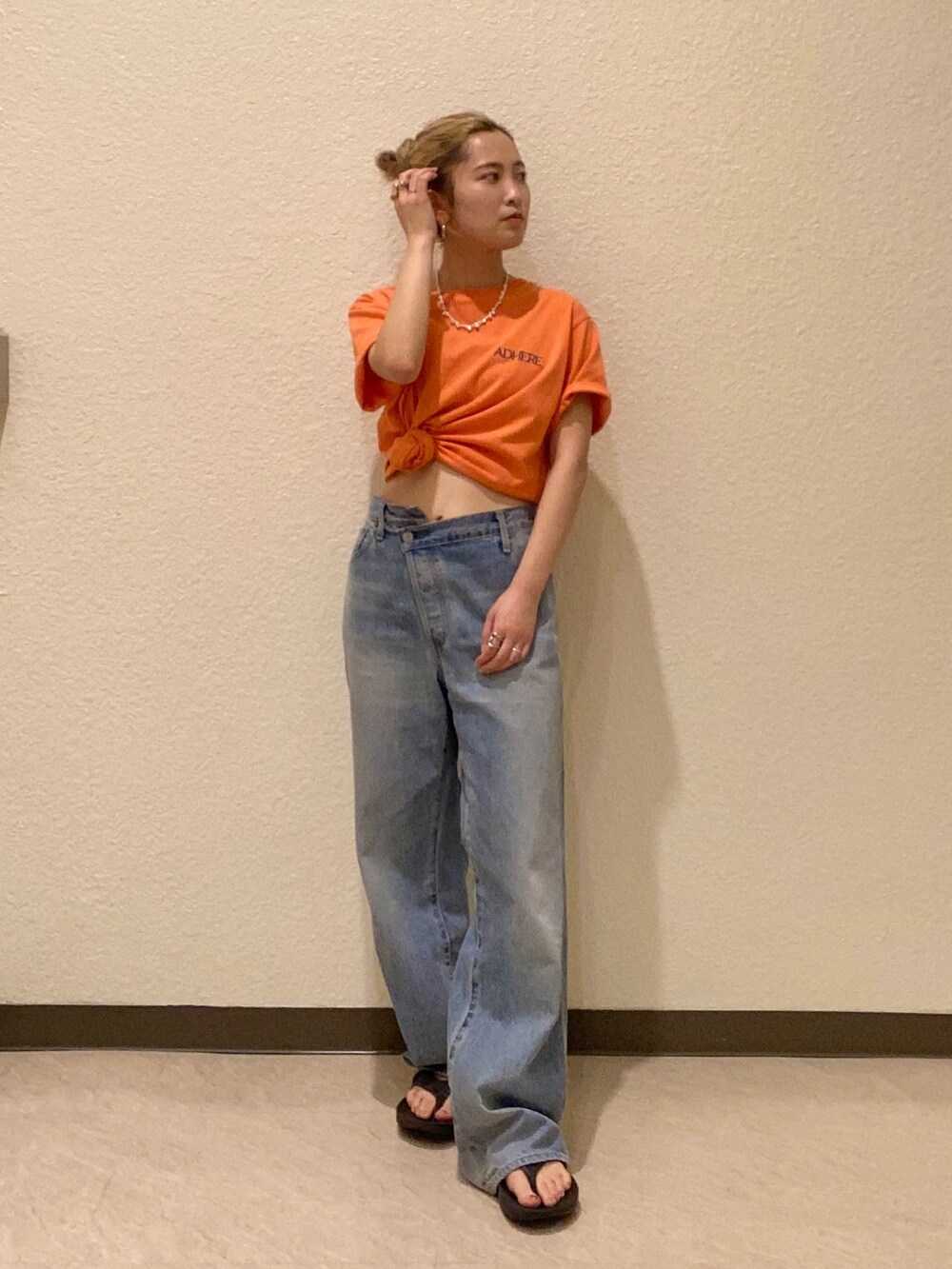 オレンジ系のTシャツ/カットソー、ブルー系のデニムパンツを着用したレディースの夏コーディネートの2枚目の写真
