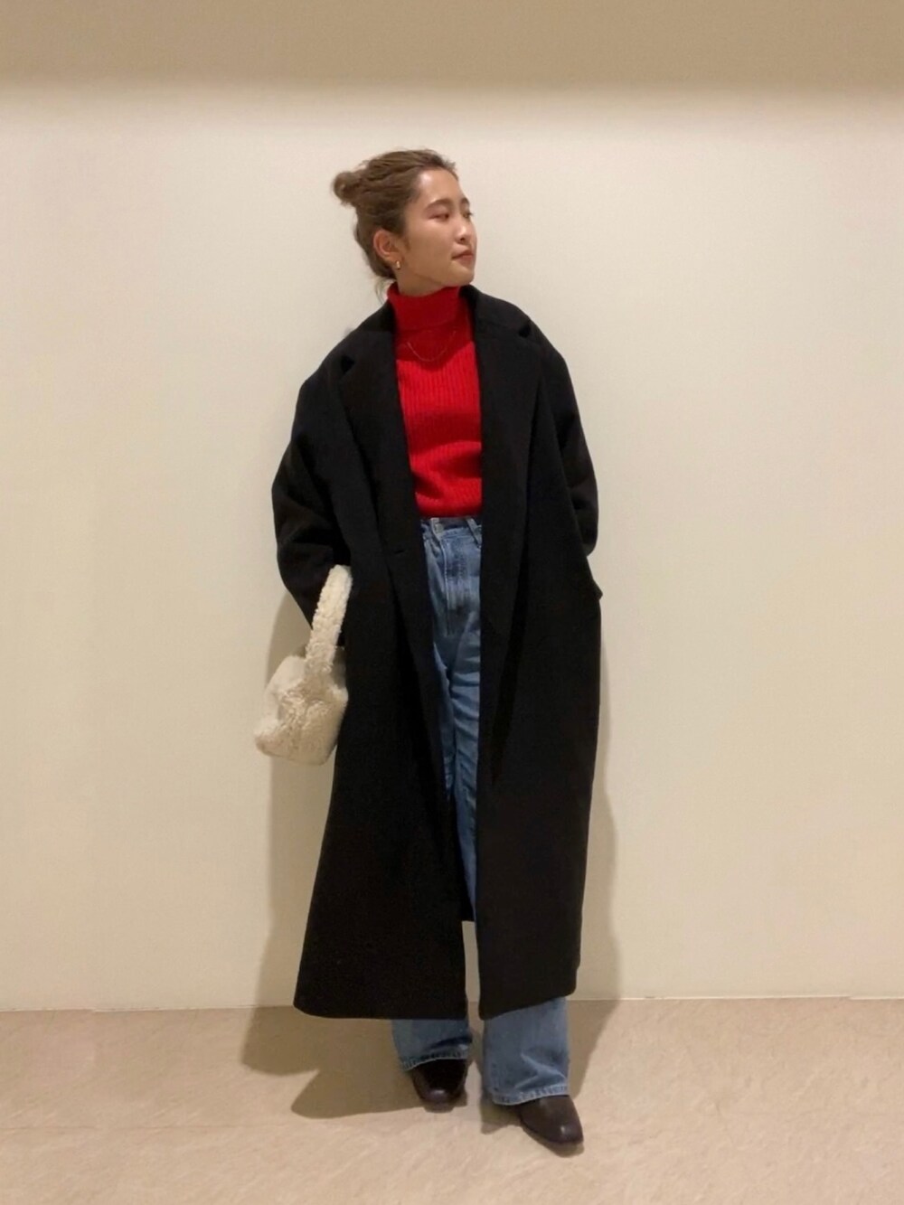 レッド系のニット/セーター、ホワイト系のハンドバッグ、ブラウン系のブーツを着用したレディースの冬コーディネートの2枚目の写真