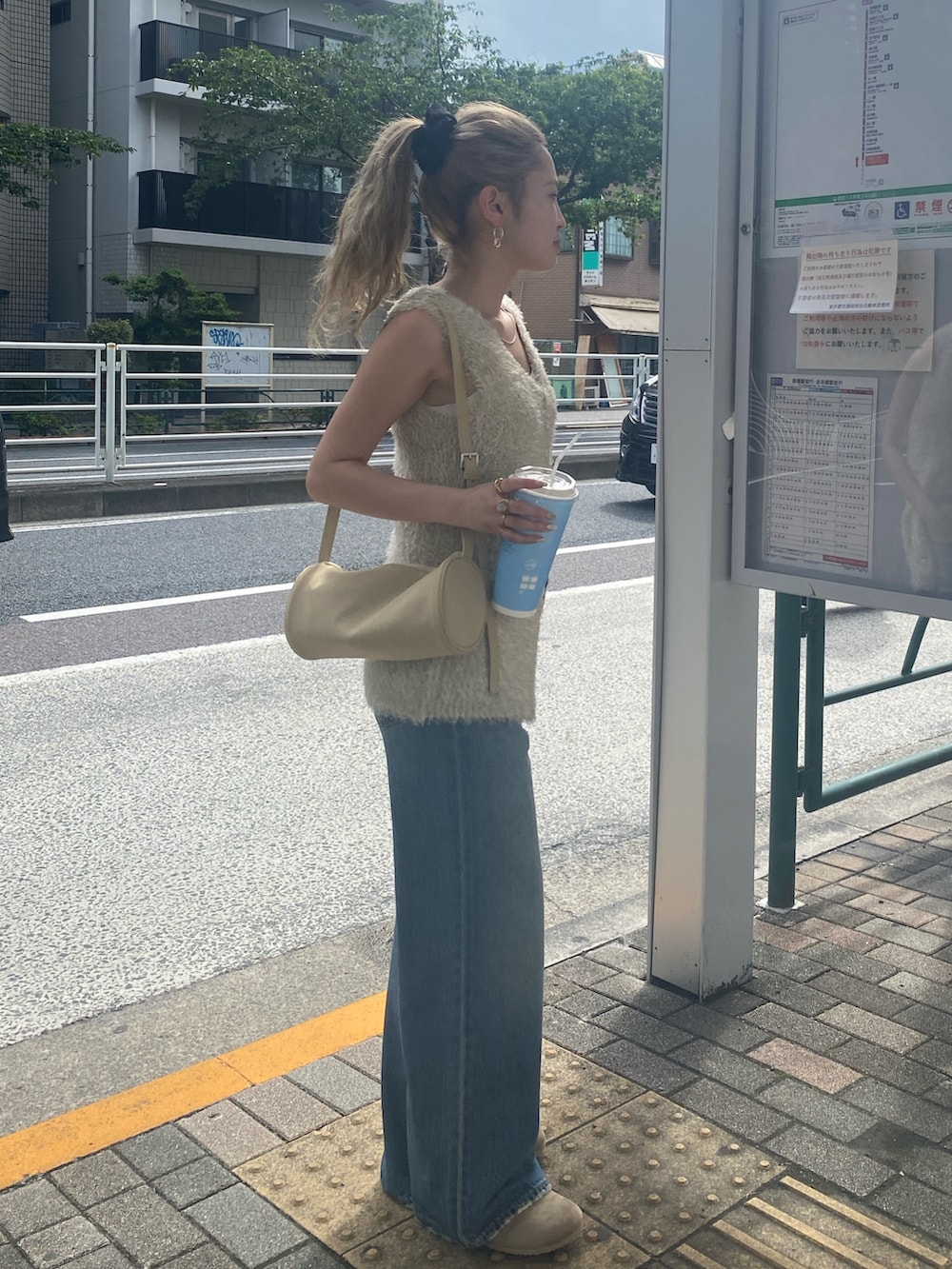 ゴールド系のニット/セーター、ブルー系のデニムパンツを着用したレディースの夏コーディネートの3枚目の写真