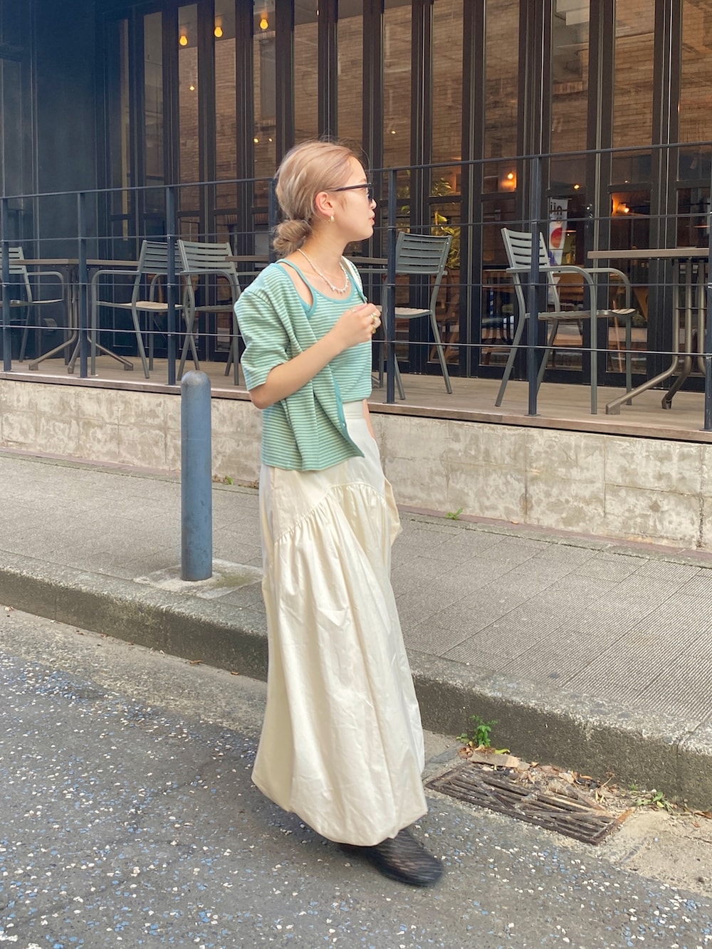 イエロー系のキャミソール、ホワイト系のスカートを着用したレディースの秋コーディネートの2枚目の写真