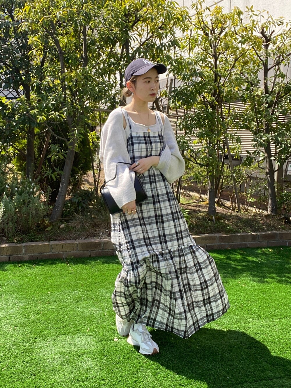 ホワイト系のニット/セーター、ブラック系のワンピース、ブラック系のハンドバッグを着用したレディースの春コーディネートの6枚目の写真