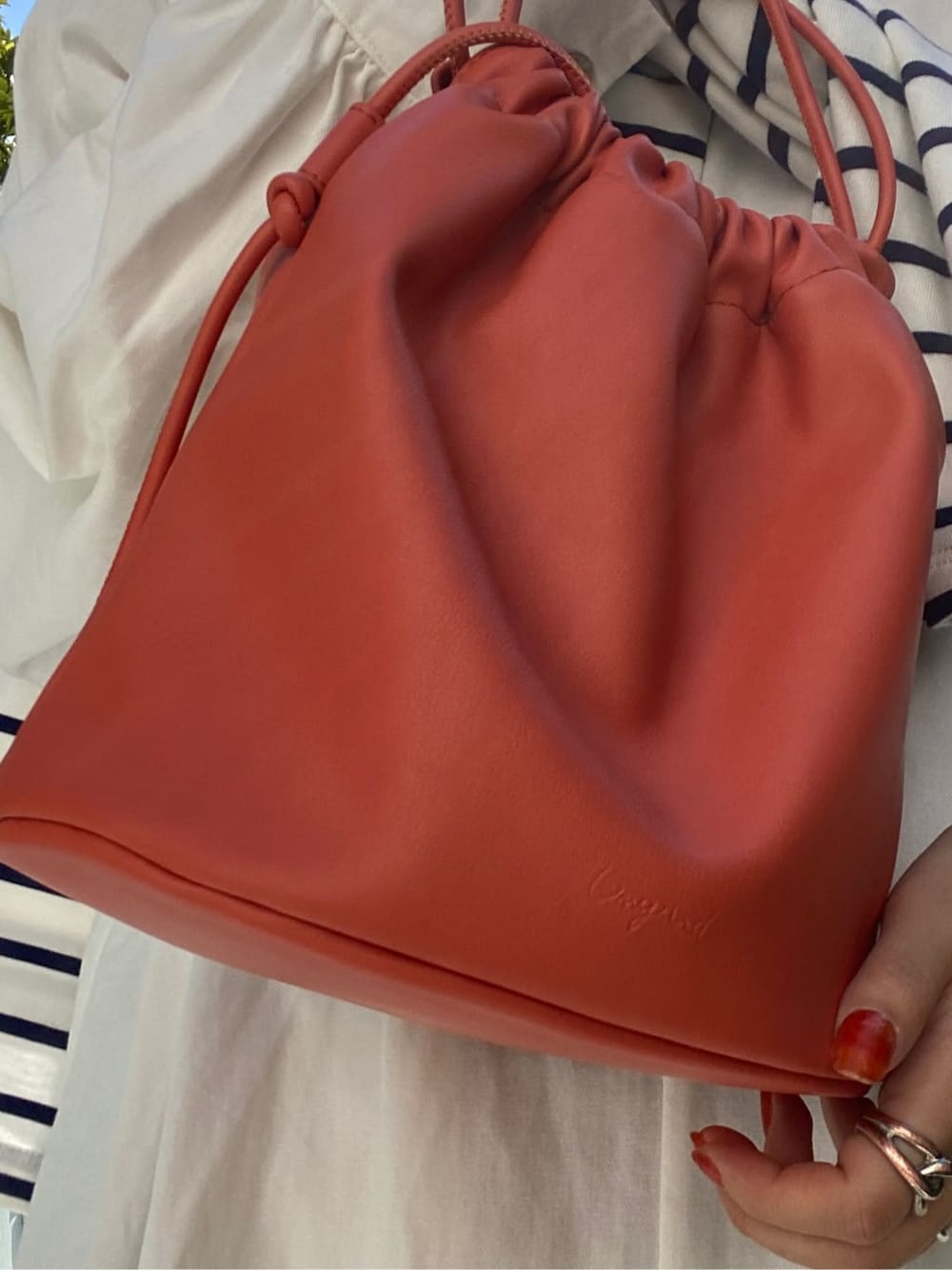 オレンジ系のハンドバッグ、オレンジ系のワンピース、ブルー系のTシャツ/カットソーを着用したレディースの秋コーディネートの7枚目の写真