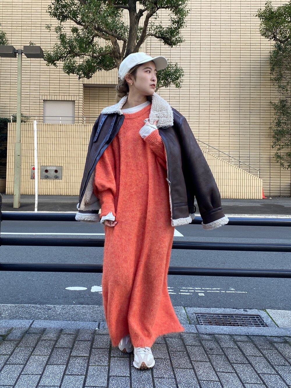 オレンジ系のワンピース、ブラウン系のブルゾン、ホワイト系のTシャツ/カットソーを着用したレディースの冬コーディネートの3枚目の写真