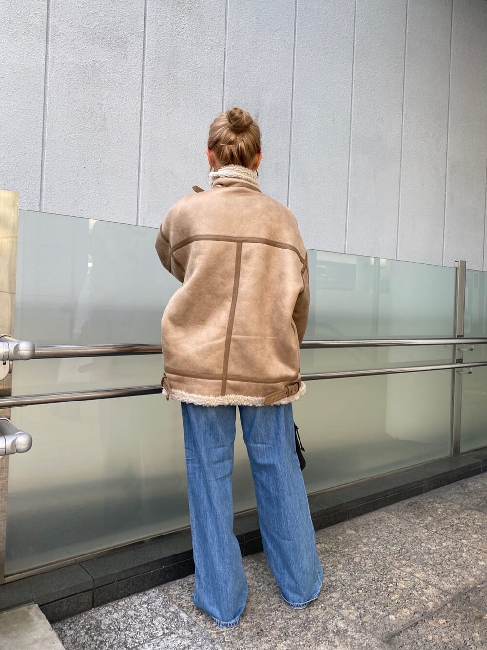 ブルー系のデニムパンツ、ブラック系のブーツ、ブラック系のハンドバッグを着用したレディースの秋コーディネートの5枚目の写真