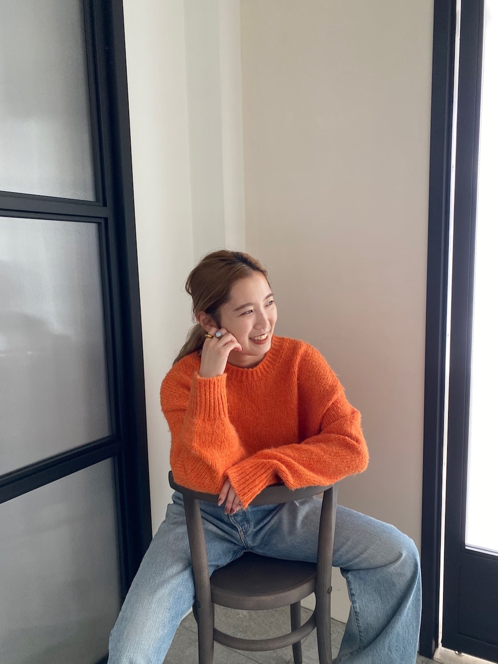 オレンジ系のニット/セーター、ブルー系のデニムパンツを着用したレディースの冬コーディネートの8枚目の写真