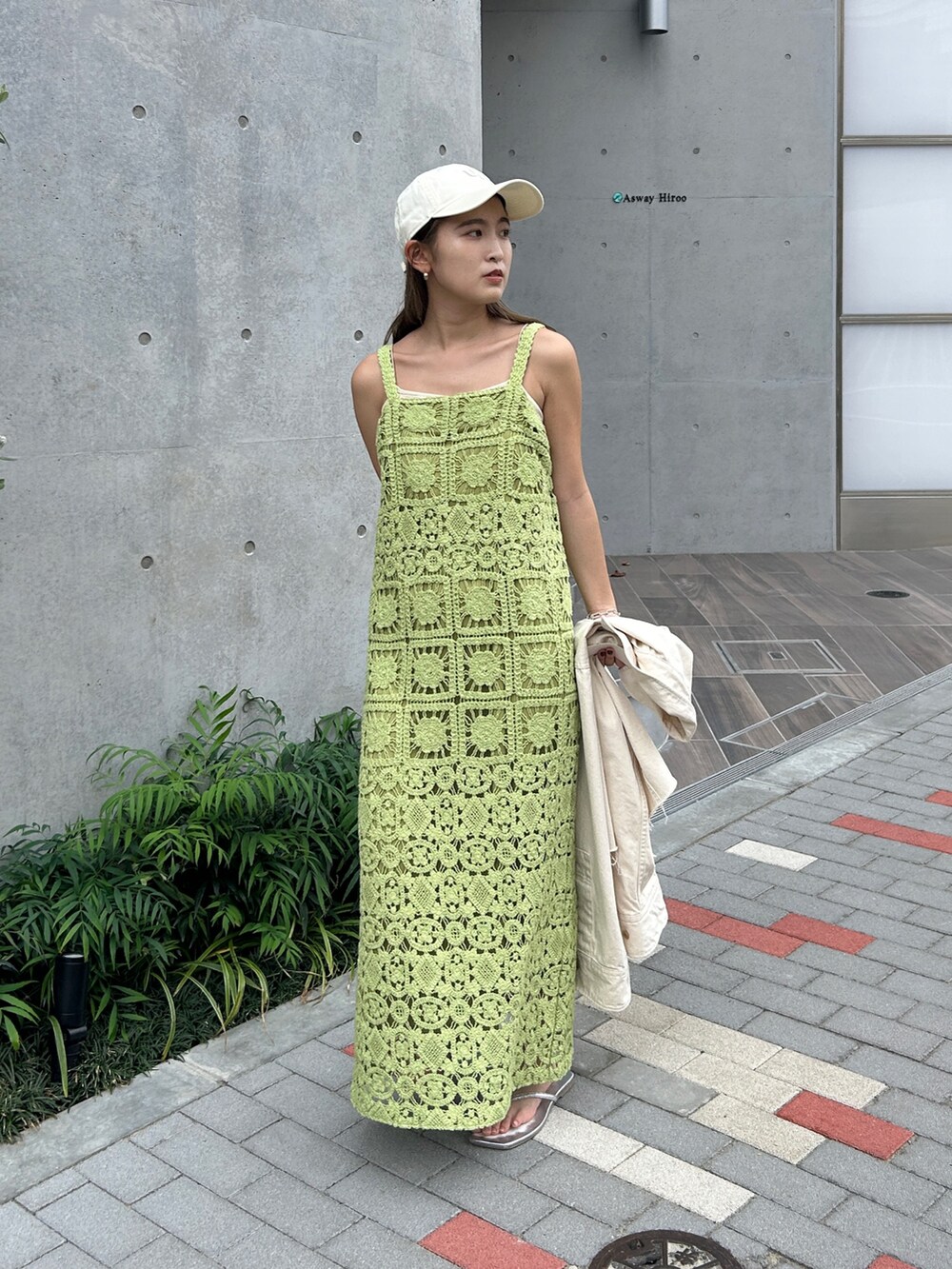 グリーン系のワンピース、ホワイト系のシャツ/ブラウス、ホワイト系のキャップを着用したレディースの春コーディネートの2枚目の写真