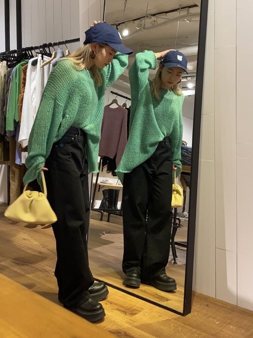 グリーン系のニット/セーター、ブラック系のデニムパンツ、ブラック系のブーツを着用したレディースの秋コーディネートの2枚目の写真