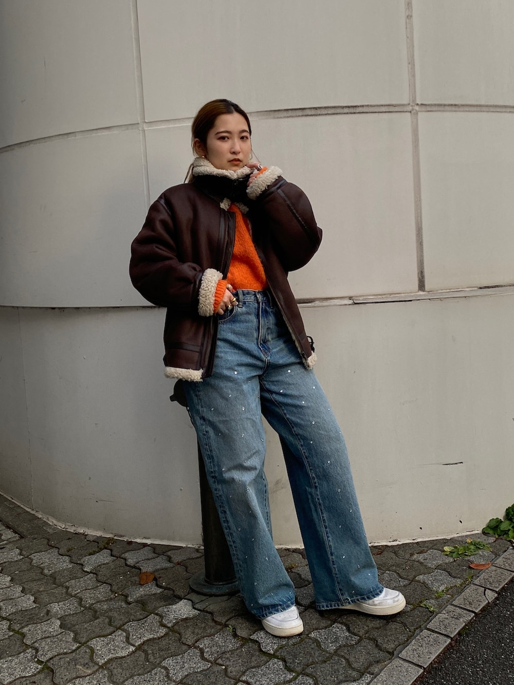 オレンジ系のニット/セーター、ブラウン系のムートンコート、ブルー系のデニムパンツを着用したレディースの冬コーディネートの3枚目の写真