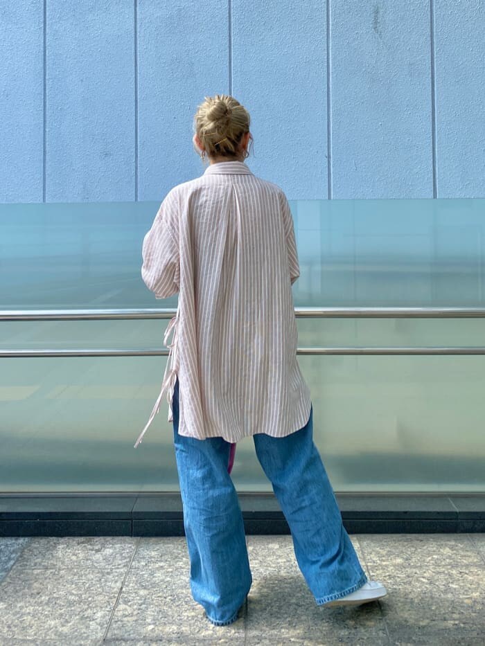 ピンク系のシャツ/ブラウス、ピンク系のハンドバッグ、ブルー系のデニムパンツを着用したレディースの春コーディネートの3枚目の写真