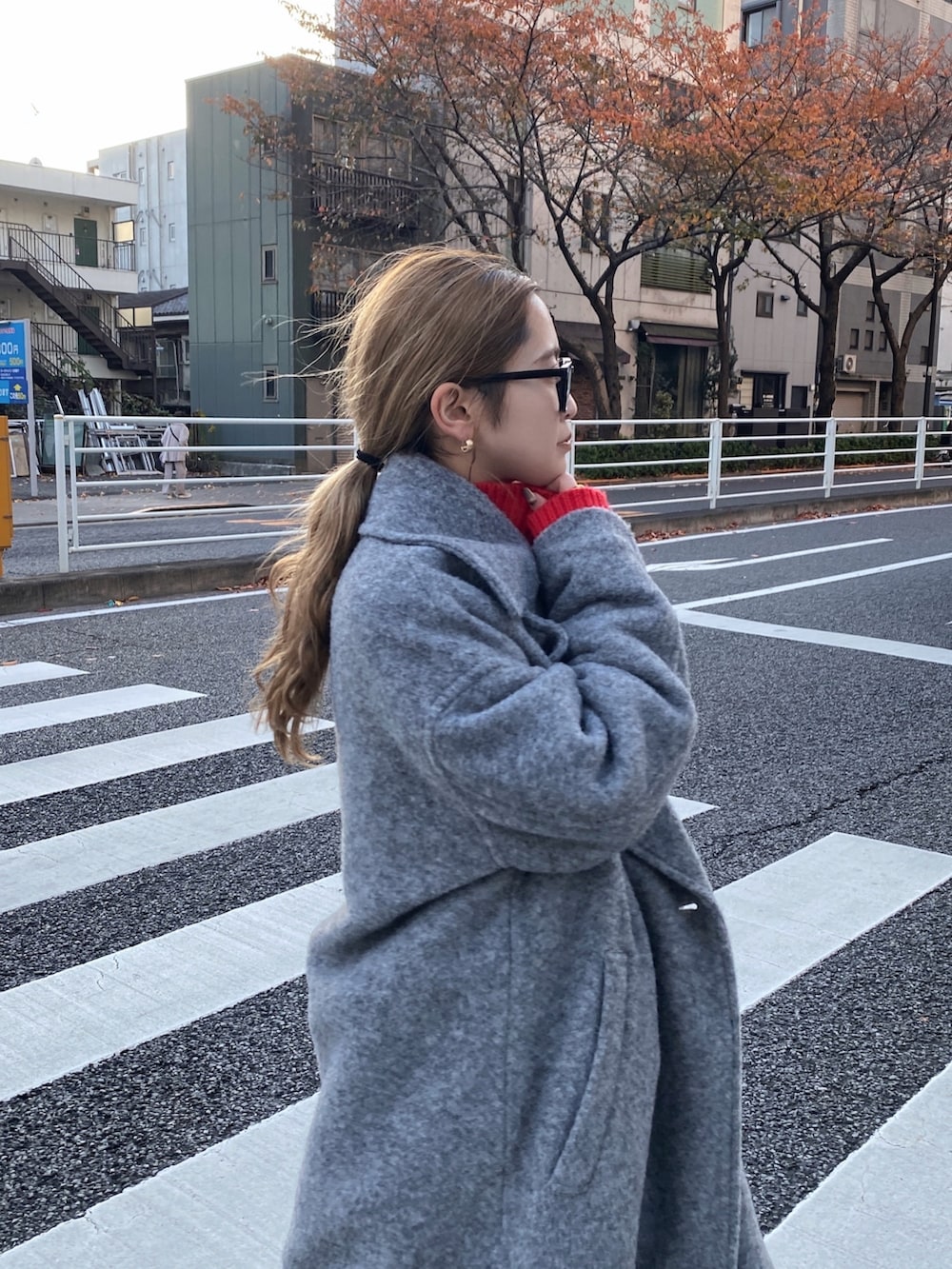レッド系のニット/セーター、グレー系のチェスターコート、ブルー系のデニムパンツを着用したレディースの冬コーディネートの4枚目の写真