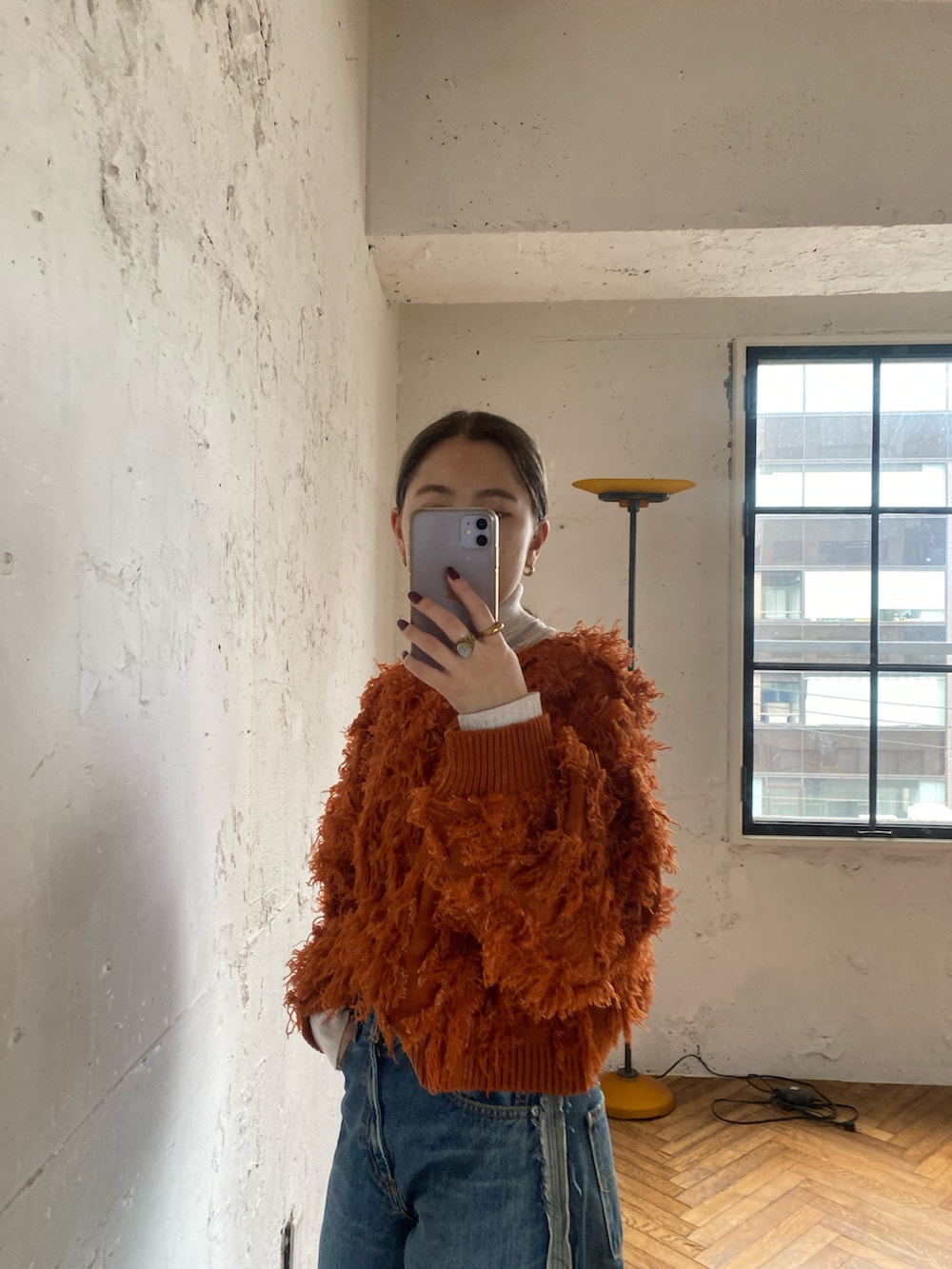 オレンジ系のニット/セーター、ホワイト系のニット/セーター、ブルー系のデニムパンツを着用したレディースの秋コーディネートの3枚目の写真