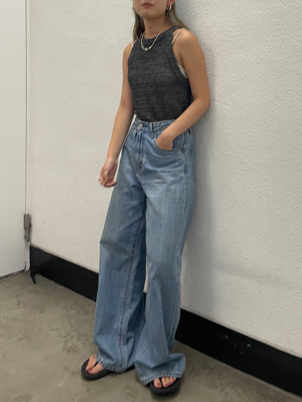 ブラック系のニット/セーター、ホワイト系のキャミソール、ブルー系のデニムパンツを着用したレディースの夏コーディネートの2枚目の写真